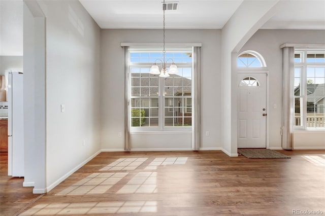 entryway featuring wood finished floors, a notable chandelier, visible vents, baseboards, and arched walkways