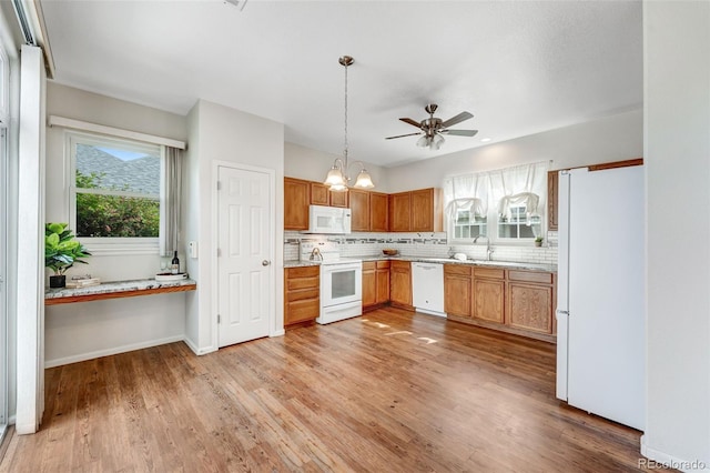 kitchen featuring white appliances, healthy amount of natural light, decorative backsplash, and light wood-type flooring