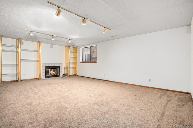 11196 E Baltic Dr, Aurora, CO 80014 - unfurnished living room with light carpet, a fireplace, a textured ceiling, and rail lighting