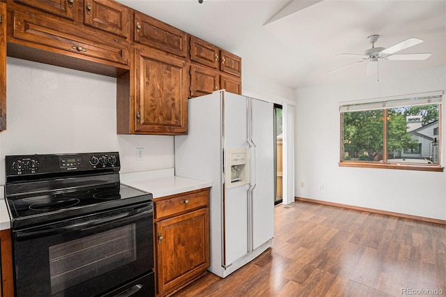 11196 E Baltic Dr, Aurora, CO 80014 - kitchen with electric range, white fridge with ice dispenser, wood finished floors, light countertops, and vaulted ceiling