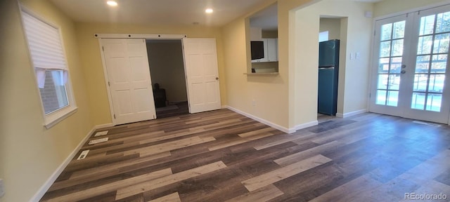 unfurnished bedroom featuring french doors, dark hardwood / wood-style flooring, black fridge, and connected bathroom