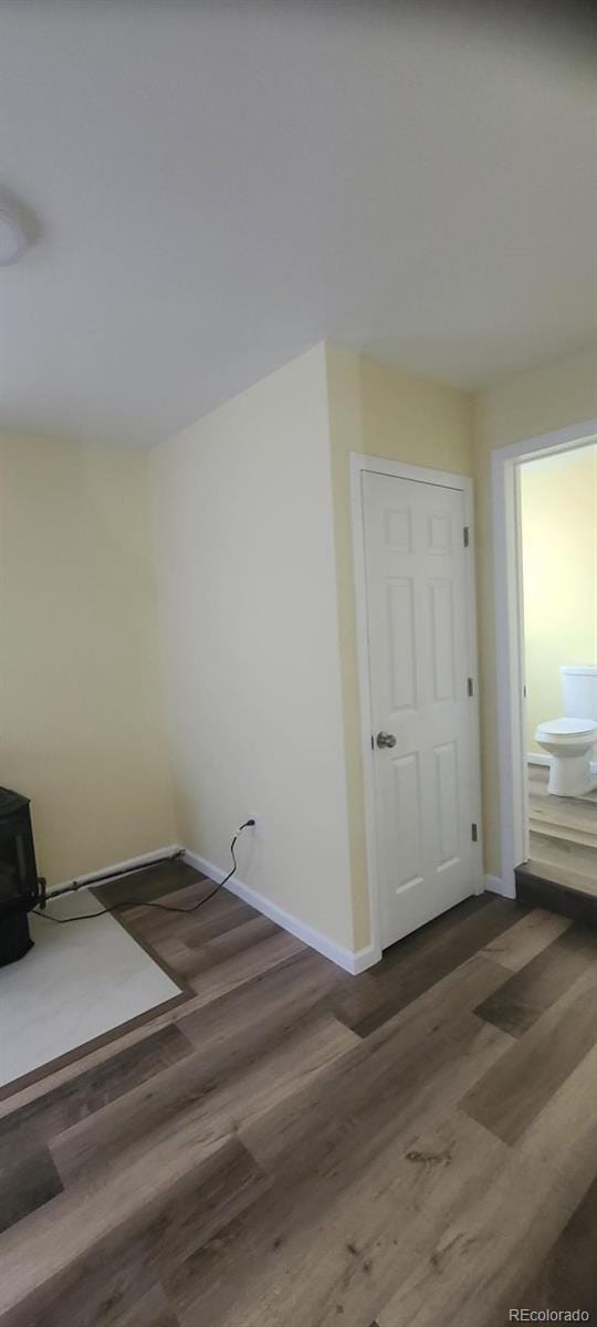 unfurnished room featuring a wood stove and dark wood-type flooring