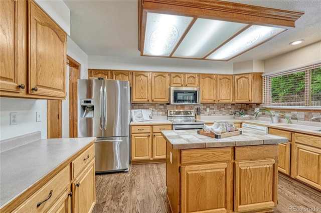 19149 E Ida Dr, Aurora, CO 80015 - kitchen featuring appliances with stainless steel finishes, light countertops, light wood-style floors, decorative backsplash, and a kitchen island