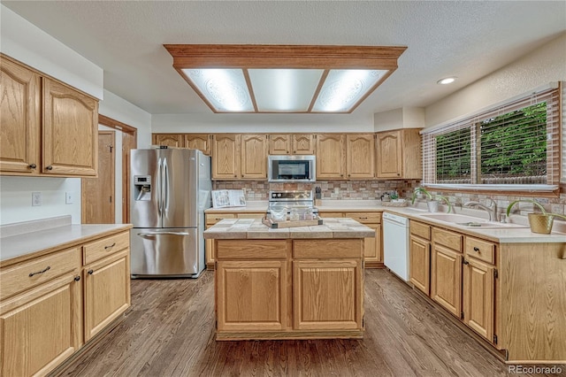 19149 E Ida Dr, Aurora, CO 80015 - kitchen featuring stainless steel appliances, wood finished floors, backsplash, a center island, and light brown cabinetry
