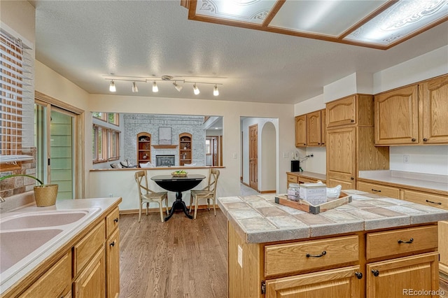 19149 E Ida Dr, Aurora, CO 80015 - kitchen featuring light countertops, a sink, light wood-type flooring, arched walkways, and a kitchen island