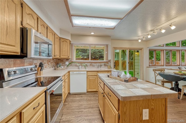 19149 E Ida Dr, Aurora, CO 80015 - kitchen featuring stainless steel appliances, light wood-style floors, tile counters, backsplash, and a textured ceiling