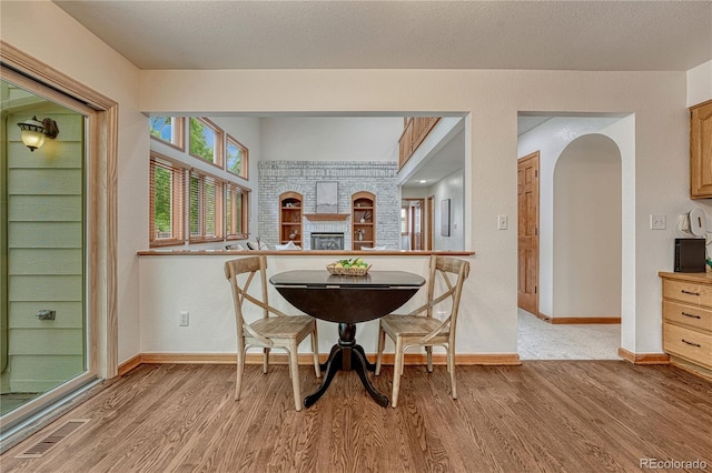 19149 E Ida Dr, Aurora, CO 80015 - dining area featuring light wood-style flooring, baseboards, arched walkways, and a brick fireplace