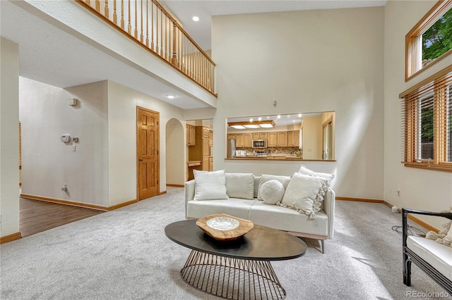 19149 E Ida Dr, Aurora, CO 80015 - living area featuring light colored carpet, baseboards, arched walkways, a high ceiling, and recessed lighting