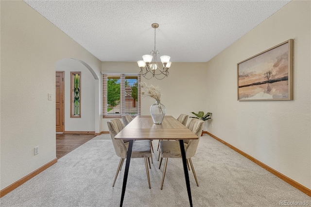 19149 E Ida Dr, Aurora, CO 80015 - dining area with carpet floors, arched walkways, a textured ceiling, baseboards, and a chandelier