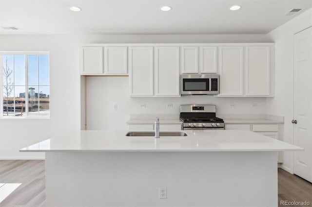 kitchen featuring sink, light hardwood / wood-style flooring, a kitchen island with sink, stainless steel appliances, and white cabinets