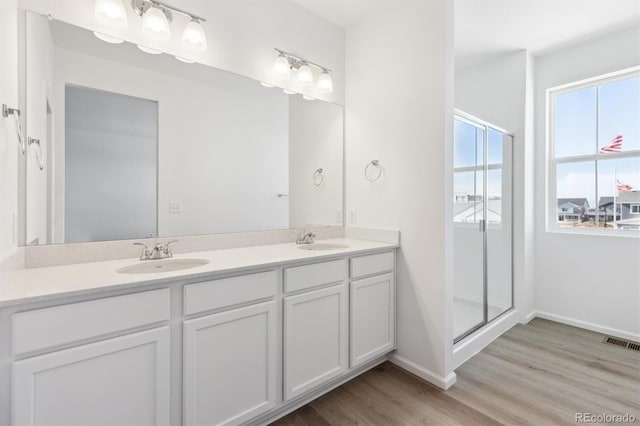 bathroom featuring hardwood / wood-style flooring, vanity, and a shower with door