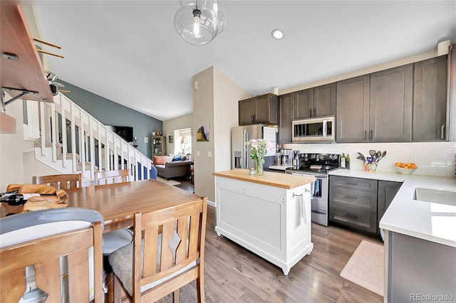 9446 W Wagon Trail Cir, Littleton, CO 80123 - kitchen featuring appliances with stainless steel finishes, vaulted ceiling, decorative backsplash, wood finished floors, and wooden counters
