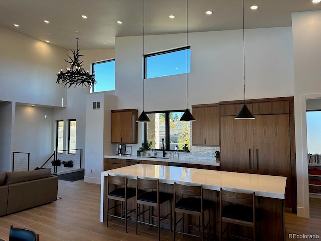 kitchen featuring backsplash, light wood-type flooring, sink, high vaulted ceiling, and a kitchen island