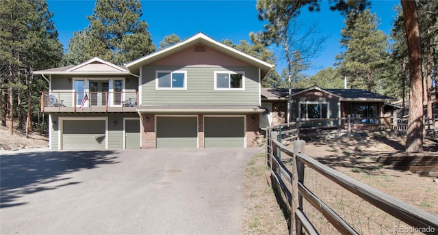 view of front of house with aphalt driveway, brick siding, a balcony, and a garage