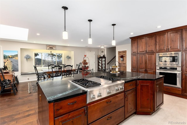 kitchen featuring a skylight, stainless steel appliances, decorative light fixtures, and recessed lighting