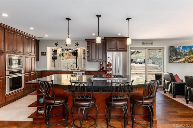 kitchen with recessed lighting, wood finished floors, a kitchen island, and appliances with stainless steel finishes