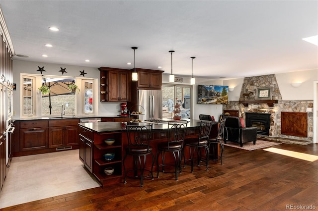 kitchen with open shelves, wood finished floors, a kitchen island, and appliances with stainless steel finishes