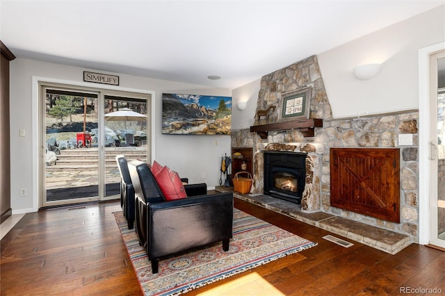 living room featuring hardwood / wood-style flooring, baseboards, visible vents, and a fireplace