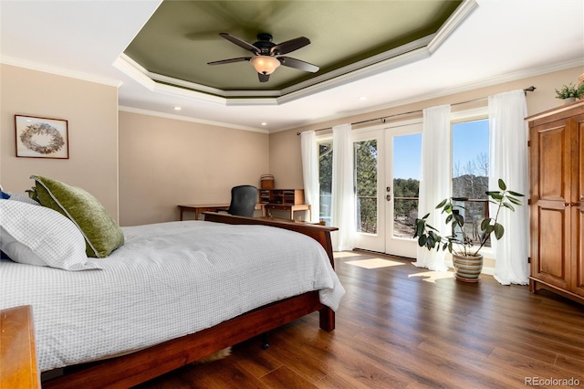 bedroom with crown molding, wood finished floors, french doors, a tray ceiling, and access to exterior