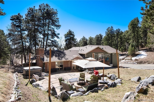 rear view of house with a patio area, brick siding, and a hot tub