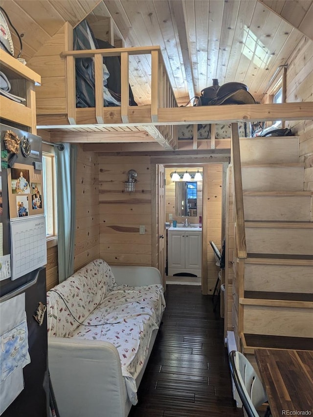 bedroom with wooden ceiling, wood walls, dark wood-type flooring, and a sink