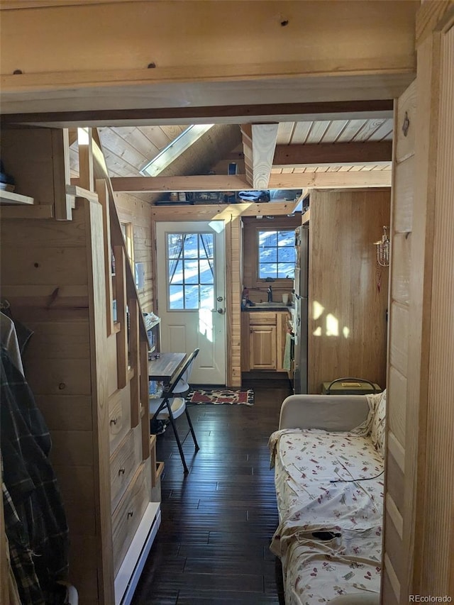 bedroom featuring wood walls, wooden ceiling, a sink, beam ceiling, and dark wood-style flooring