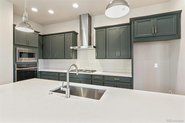 kitchen featuring decorative backsplash, appliances with stainless steel finishes, wall chimney exhaust hood, sink, and pendant lighting