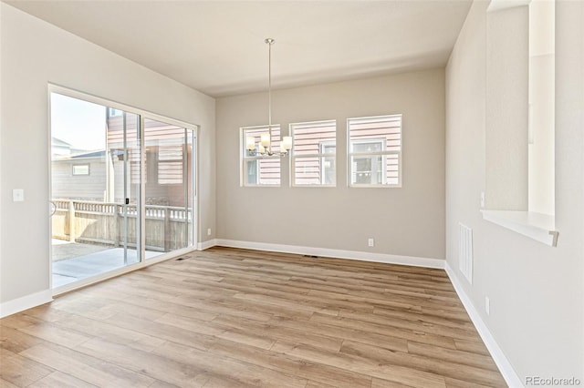 unfurnished dining area with hardwood / wood-style floors, a healthy amount of sunlight, and an inviting chandelier