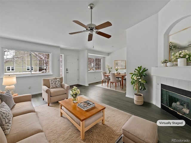 living room featuring a tiled fireplace, ceiling fan, dark hardwood / wood-style flooring, and lofted ceiling