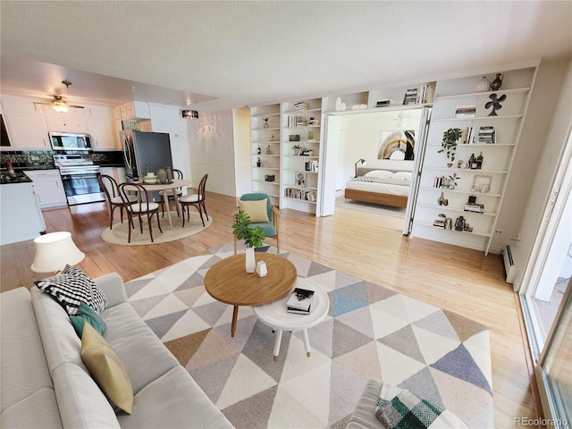 715 S Alton Way Unit 10A, Denver, CO 80247 - living area with light wood finished floors, baseboard heating, healthy amount of natural light, and a textured ceiling