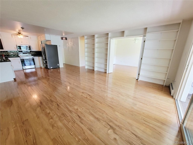 715 S Alton Way Unit 10A, Denver, CO 80247 - unfurnished living room featuring built in shelves, light wood-style floors, and baseboard heating