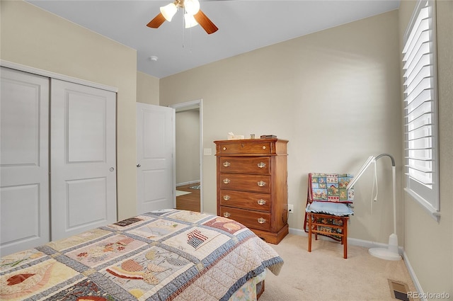 bedroom with ceiling fan, light carpet, and a closet