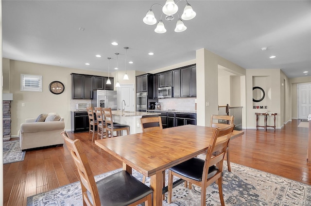 dining room with wood-type flooring, sink, and an inviting chandelier