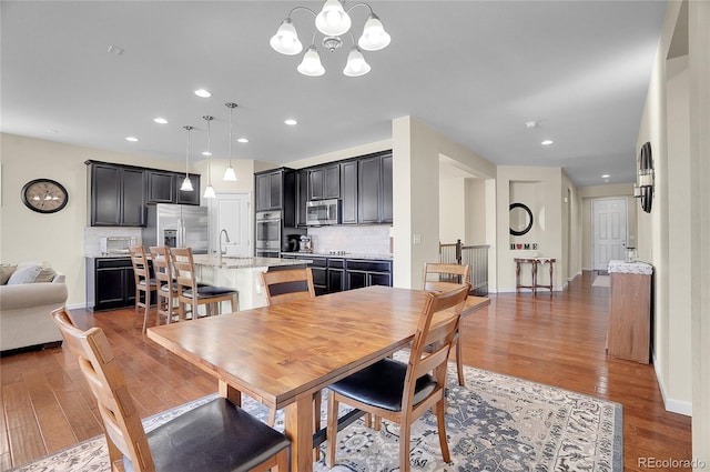 dining room featuring an inviting chandelier, sink, and dark wood-type flooring