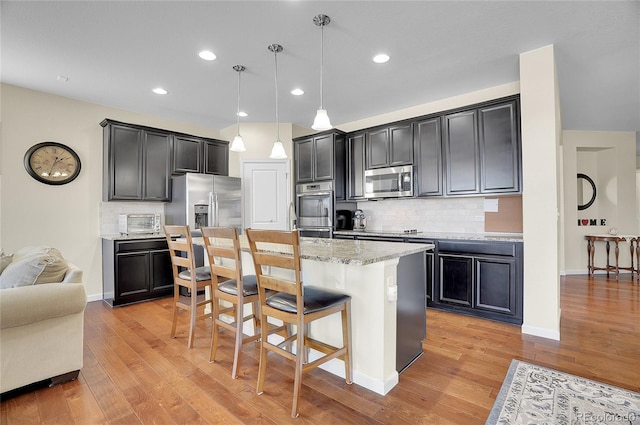 kitchen with backsplash, decorative light fixtures, stainless steel appliances, and a kitchen island