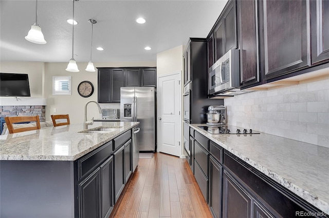 kitchen with pendant lighting, sink, a breakfast bar area, appliances with stainless steel finishes, and a center island with sink