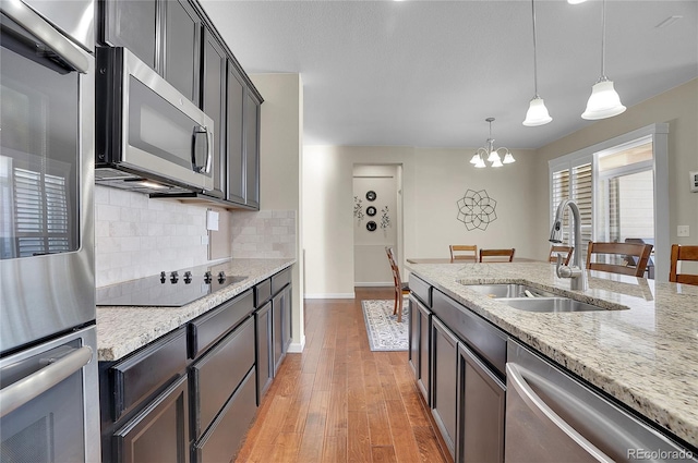 kitchen featuring sink, decorative light fixtures, stainless steel appliances, light stone countertops, and decorative backsplash