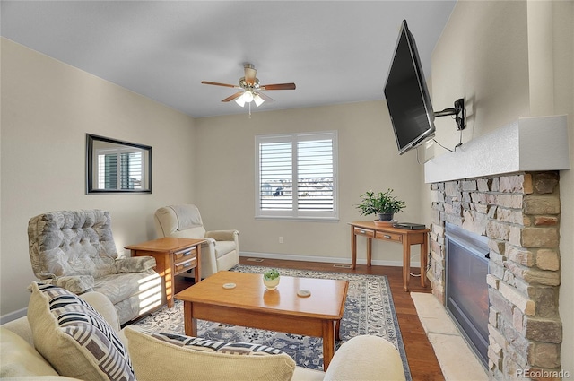 living room featuring ceiling fan, a fireplace, and light hardwood / wood-style flooring