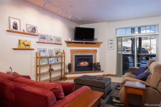 living room with a tiled fireplace, carpet, and rail lighting