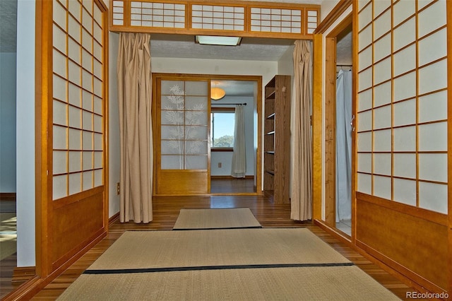 hallway featuring hardwood / wood-style flooring, wood walls, and french doors