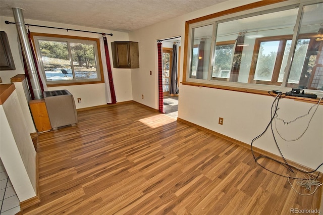 unfurnished room featuring hardwood / wood-style floors, a textured ceiling, and a healthy amount of sunlight