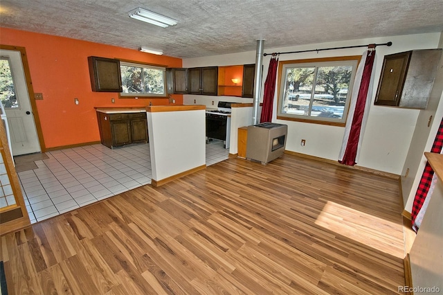 kitchen featuring light wood-type flooring, white gas stove, and dark brown cabinetry