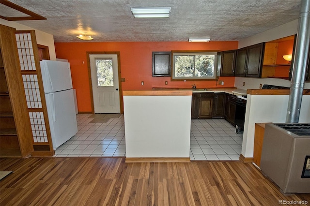 kitchen featuring white fridge, light hardwood / wood-style floors, and dark brown cabinetry