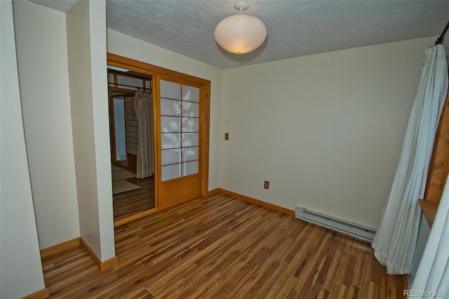 empty room featuring baseboard heating and dark hardwood / wood-style floors