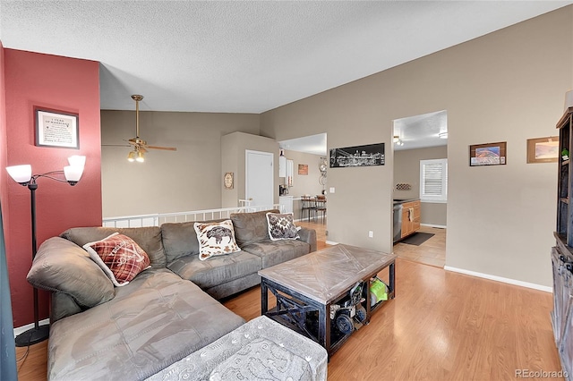 living room with a textured ceiling, ceiling fan, light hardwood / wood-style flooring, and lofted ceiling