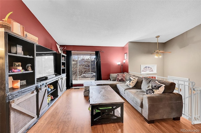 living room featuring lofted ceiling, ceiling fan, a textured ceiling, and hardwood / wood-style flooring