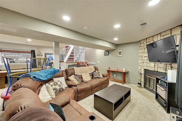 carpeted living room featuring a textured ceiling and a stone fireplace