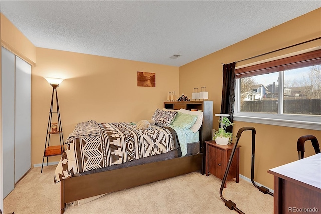 bedroom featuring light colored carpet and a textured ceiling