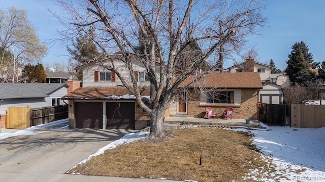 view of front of house featuring driveway, an attached garage, fence, and brick siding