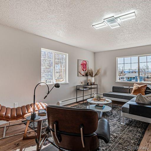 living room featuring a baseboard radiator, a textured ceiling, and dark wood-type flooring